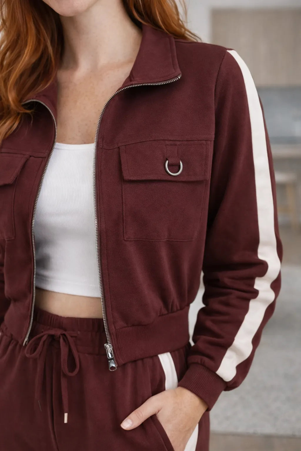 Mulher usando conjunto listrado feminino marrom com jaqueta de zíper e calça pantalona em tecido sensorial. Detalhes